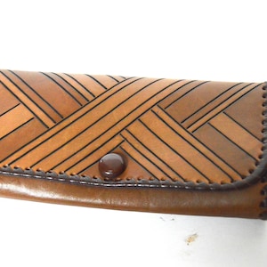 Puede incluir: Una cartera de cuero marrón con un patrón tejido y un cierre de botón marrón.