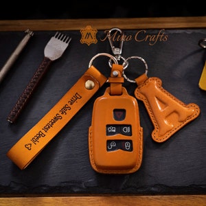 May include: A brown leather key chain with a key fob cover and a charm that says "A". The key chain has a strap that says "Drive Safe Sweetest Boo!"