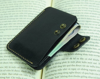 May include: A black leather wallet with a brown stitch detail and two brass snaps. The wallet is open and has bills inside.