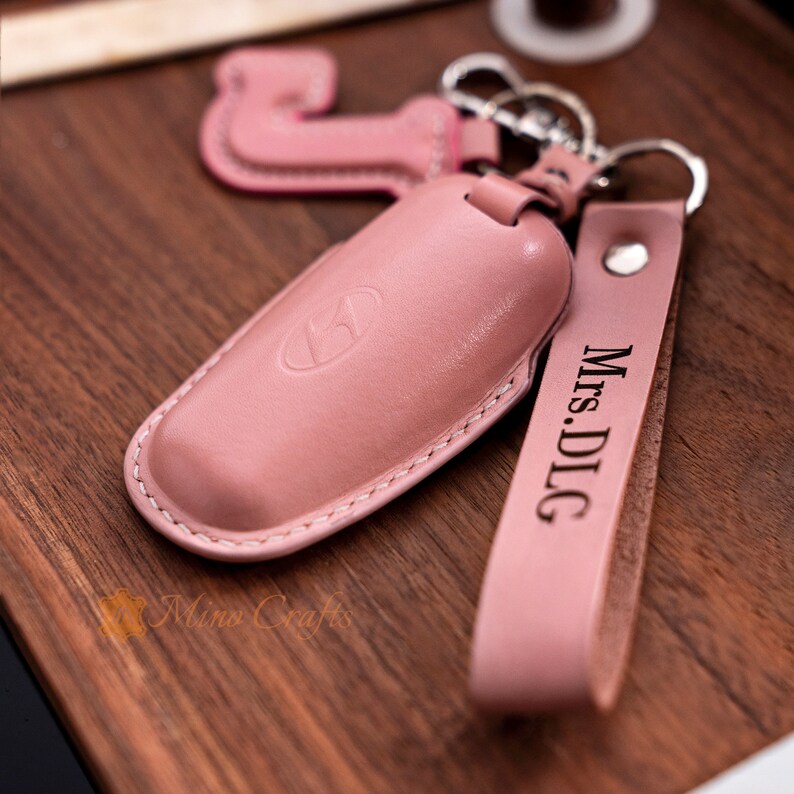 May include: A pink leather key chain with a key fob and a personalised tag that says "Mrs. DLG".