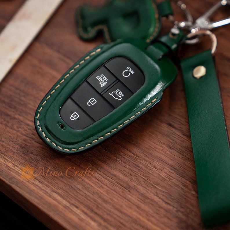 May include: Green leather key fob with stitching and four buttons labelled "Hold", "Hold", "Rear", and a lock icon.