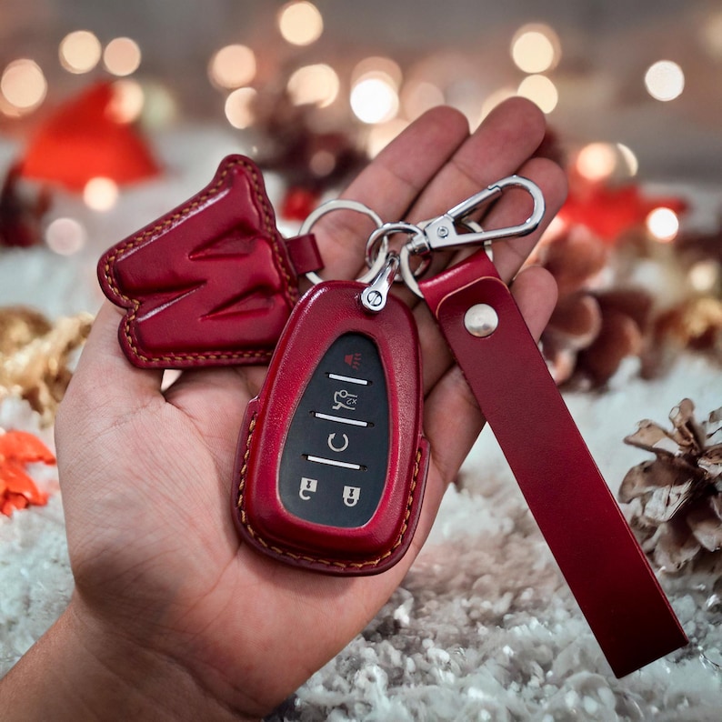 Op de afbeelding: Rode leren sleutelhanger met een zilveren sleutelring en een rode leren band. De sleutelhanger heeft een rode leren hoes met een zilveren sleutel erin.