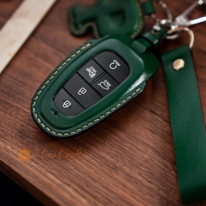 May include: Green leather key fob with stitching and four buttons labeled "Hold", "Hold", "Rear", and a lock icon.