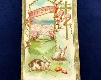 Carte postale de Pâques « Salutations de Pâques » Croix d’or Lapins Oeufs Meadow Circa 1910-1920 Carte postale antique utilisée