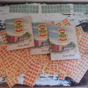 Puede incluir: Un surtido de sellos antiguos y libros de ahorro de sellos. Los libros muestran el texto "TOP VALUE STAMPS" y "Saver Book". Los sellos son principalmente rojos y amarillos, con algunos sellos verdes visibles.