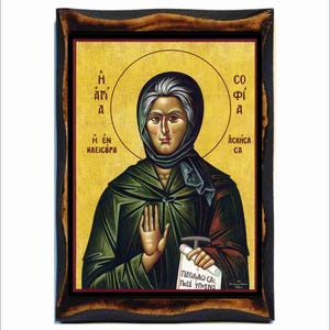 May include: A religious icon depicting a woman in a green robe holding a scroll with Greek text. The icon is framed in a dark wood frame. The text on the scroll reads "Παράκλησις σας" and "Ποιάι ύψος Να".