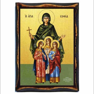 May include: Religious icon featuring a central figure in a green robe holding a cross, surrounded by three figures. The icon has gold and green backgrounds, with text in Greek. The frame is dark brown.