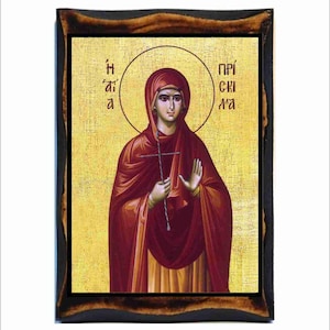 May include: A religious icon of a woman in a red robe holding a cross. The icon is framed in a dark wood frame. The text "Η άγια" is on the left side of the icon and "ΠΡΟΣΚΥΛΑ" is on the right side.