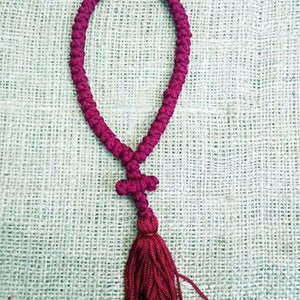May include: A maroon prayer rope with a tassel and a small red bead at the top.