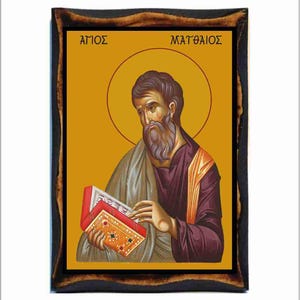 Puede incluir: Un icono enmarcado de San Mateo, una figura religiosa, sosteniendo un libro. El icono está pintado en un estilo tradicional con colores vibrantes y detalles dorados. El marco es de madera marrón oscuro con un diseño tallado.