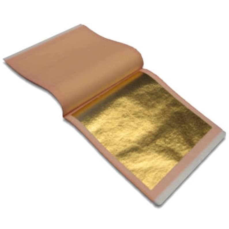 Puede incluir: Una hoja de pan de oro, envuelta en papel protector, lista para usar en manualidades y proyectos de arte.