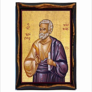Può includere: Un'icona dipinta a mano di San Paolo, una figura religiosa, con sfondo dorato e cornice in legno. L'icona raffigura San Paolo che tiene un rotolo nella mano destra e fa un gesto con la mano sinistra. Il testo "O AΓΙΟς ΠΑΥΛΟς" è scritto in greco sull'icona.