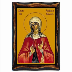May include: A religious icon depicting Saint Anthusa the Younger. The icon is painted in a traditional Byzantine style with a gold background and a red robe. The saint is depicted with her hands raised in prayer.