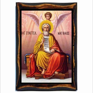 Puede incluir: Un icono religioso que representa a San Mateo, uno de los cuatro evangelistas, sentado en un trono con un rollo en la mano. Lleva una túnica amarilla y una capa roja. Un ángel con alas flota sobre él. El icono está enmarcado en un marco de madera oscura. El texto "ΑΓ. ΕΥΑΓΓΕΛ." y "ΜΑΤΘΑΙΟΣ" está escrito en griego en la parte superior del icono.