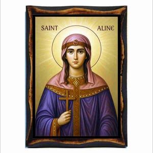 Könnte beinhalten: Eine Ikone der Heiligen Aline, die eine Frau in einem lila Gewand und einer rosa Kopfbedeckung zeigt, die ein Kreuz hält. Das Bild hat einen goldenen Heiligenschein und ist in einem dunklen, verzierten Holzrahmen gerahmt. Der Text "SAINT ALINE" steht oben.