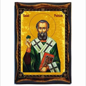 Op de afbeelding: Een religieus icoon van Sint Patrick, een christelijke heilige en beschermheilige van Ierland, afgebeeld in een traditionele stijl. Hij houdt een klavertjevier in zijn linkerhand en een boek in zijn rechterhand. Het icoon is ingelijst in een donkerhouten lijst met een gouden rand.