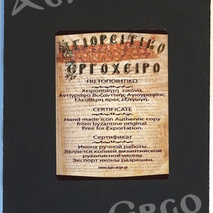 May include: A certificate of authenticity for a hand-painted icon. The certificate is printed on parchment paper with gold lettering and includes the text "Agioreitiko Ergoheiro" and "Certificate".