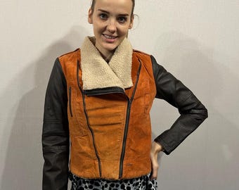 May include: A brown suede and black leather jacket with a faux fur collar. The jacket has a zip fastening and multiple pockets.