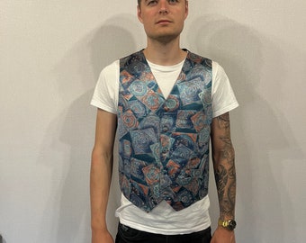 May include: A blue and orange patterned vest with a white t-shirt and black jeans.