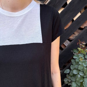 May include: A black and white t-shirt with a white square on the top half and black on the bottom half.