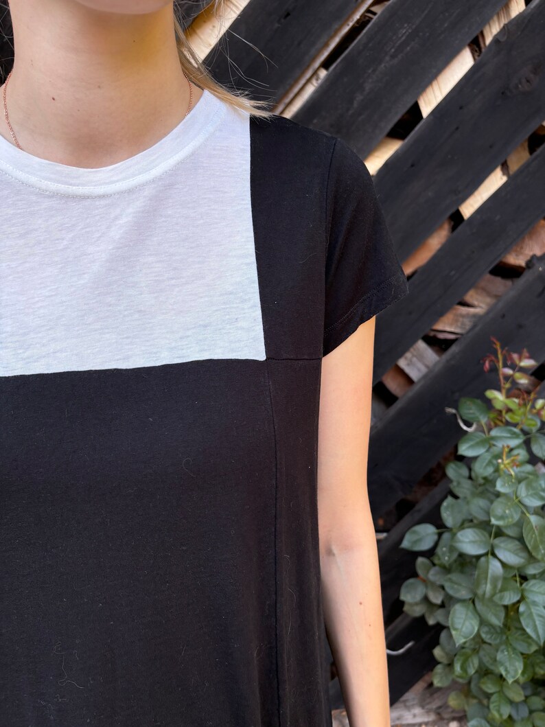 May include: A black and white t-shirt with a white square on the top half and black on the bottom half.