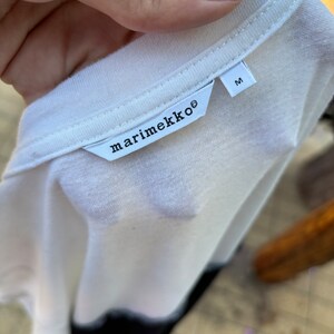 May include: White t-shirt with a black marimekko label and a size M tag.