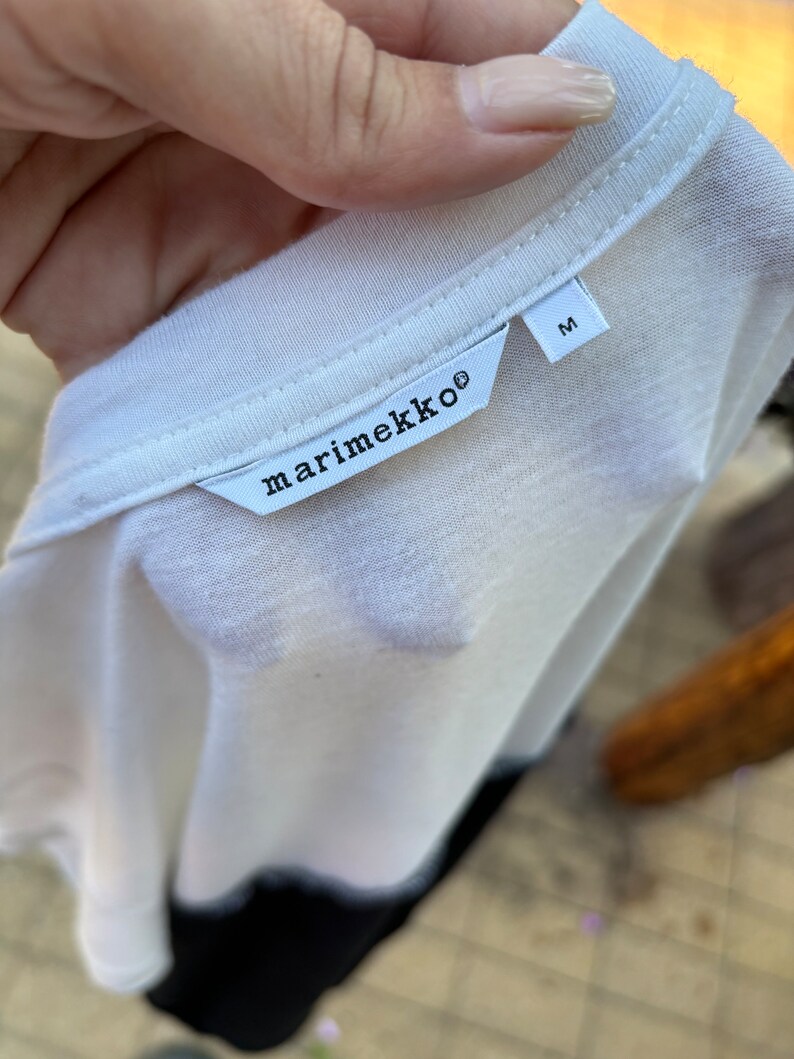 May include: White t-shirt with a black marimekko label and a size M tag.
