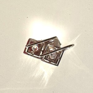 May include: Silver earrings with two square-shaped settings, each with a clear rhinestone in the center.