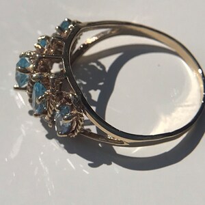 May include: A gold ring with a row of blue gemstones set in a delicate, intricate design.