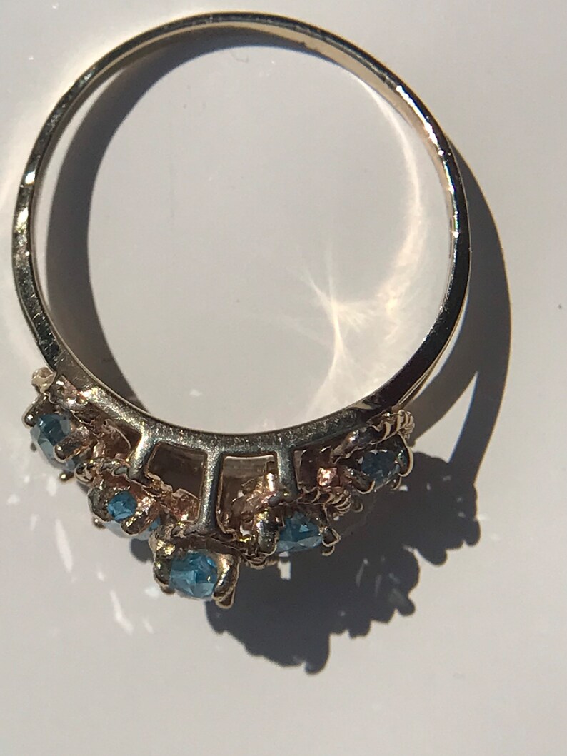 May include: A silver ring with a cluster of blue gemstones set in a delicate design.