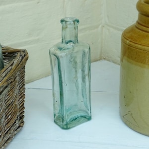 Peut inclure: Deux bouteilles en verre et un pot en céramique brun. Les bouteilles sont transparentes et ont une forme carrée. Le pot est rond et a une large ouverture.