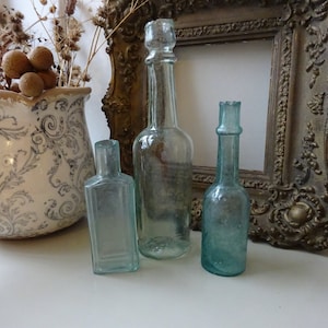 Antique aqua glass sauce bottle with burst top, one aqua glass bottle with shear top, bud vases. Bevelled rectangular, cylindrical bottles