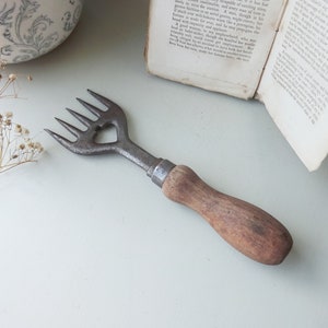 May include: A vintage metal garden tool with a wooden handle. The tool has four tines and a heart-shaped cutout in the metal.
