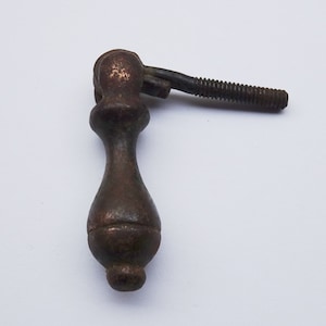 Op de afbeelding: Een vintage, donkerbruine metalen kastknop met een afgeronde, traanvormige knop en een schroef met schroefdraad.