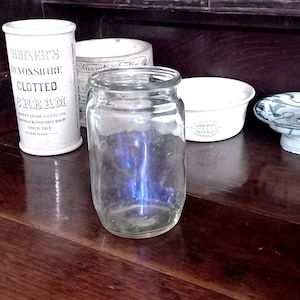 Puede incluir: Un tarro de vidrio transparente con una luz azul en su interior, sentado sobre una superficie de madera con otros tarros y cuencos.