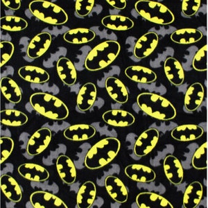 May include: A black fabric featuring a repeating pattern of Batman logos. The design consists of bright yellow oval-shaped emblems with black bat silhouettes inside, interspersed with solid grey bat silhouettes across the dark background.