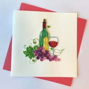 May include: A handmade paper quilling card featuring a wine bottle, a glass of red wine, and a bunch of grapes. The wine bottle is green and yellow, the grapes are purple, and the card is on a red envelope.