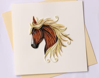 May include: A handmade greeting card featuring a detailed quilled horse head. The horse has a brown body, a white face, and a flowing blonde mane. The card is on a cream-colored background with a light yellow envelope.