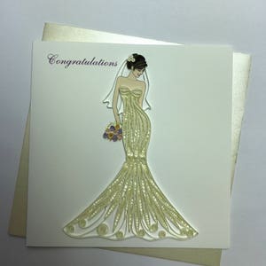 May include: A white card with the word "Congratulations" printed in purple. A bride in a white dress with a veil and a bouquet of flowers is on the card.
