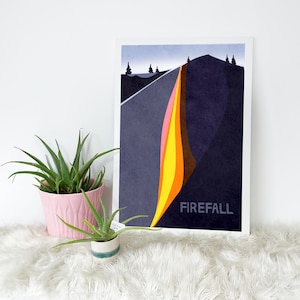 May include: A framed art print featuring a stylized landscape with a waterfall of color. The artwork showcases a dark blue mountain and road, with a vibrant cascade of pink, yellow, and orange. The word "FIREFALL" is printed in white.