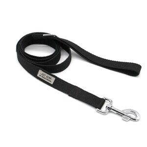 May include: Black dog leash with a silver metal clasp. The leash is made of a durable, woven material and features a small rectangular tag with the text "JUST HEMP. BY WIGGLYWOODS". The leash is coiled and ready for use.