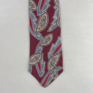 May include: A burgundy tie with a repeating paisley pattern in shades of blue, gray, and tan. The tie features red accent stripes and a classic pointed end. This formal accessory is suitable for business or special occasions.