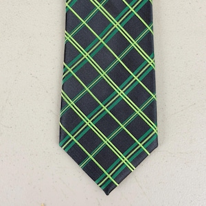 May include: A dark navy blue tie with a plaid pattern. The plaid design features intersecting lines of green and neon green, creating a grid-like pattern. The tie is made of a smooth, likely silk or satin material.