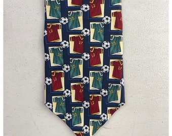 May include: A navy blue silk tie with a repeating pattern of soccer jerseys in red, green, and white with the numbers 12, 17, 20, and 30.