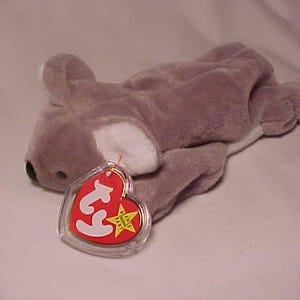 May include: A gray and white plush koala bear with a red and white Ty tag attached. The tag has the Ty logo and a star.