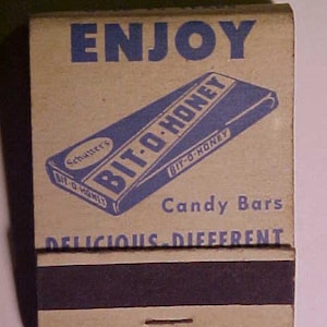 May include: A vintage matchbook cover with a blue and white design featuring the text "ENJOY" and "BIT-O-HONEY Candy Bars DELICIOUS DIFFERENT". The matchbook is brown with a black match striker.