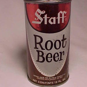 May include: Vintage Staff Root Beer can. The can features a red and white logo with the word "Staff" in a stylized font. The words "Root Beer" are prominently displayed. The can's design includes a brown and silver color scheme, with the text "Net Contents 12 fl. oz."