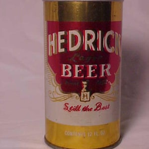 May include: A gold and red aluminum can of Hedrick Lager Beer. The can has a white label with the text "Hedrick Lager Beer" in red and white lettering. The label also includes the text "Still the Best" and "Contents 12 Fl Oz."