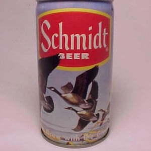 May include: A vintage aluminum can of Schmidt Beer with a blue and white background featuring a flock of geese flying in formation. The can has a red label with the text "Schmidt Beer" in white lettering. The bottom of the can has the text "Grow with the Great" in white lettering.