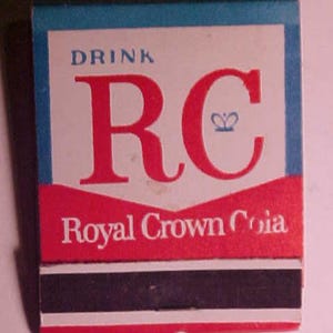 May include: A vintage matchbook with a red, white, and blue design. The text on the matchbook reads "Drink RC Royal Crown Cola".